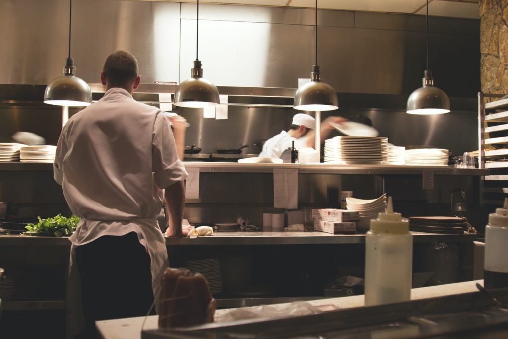 Een professionele kok bereid een private dining maaltijd met drie gangen voor gasten thuis